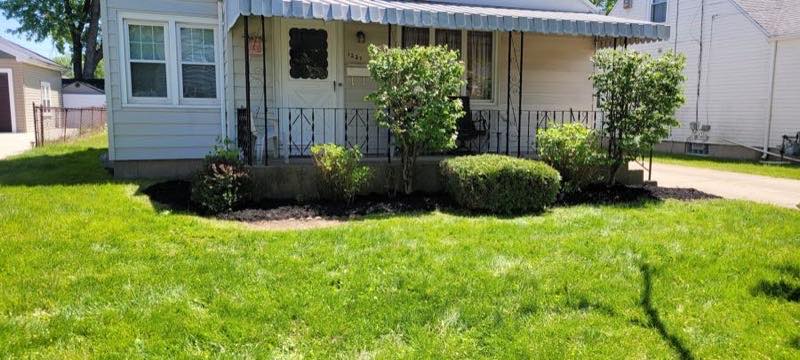 Mowed lawn and mulched shrub beds in front of a Buffalo home