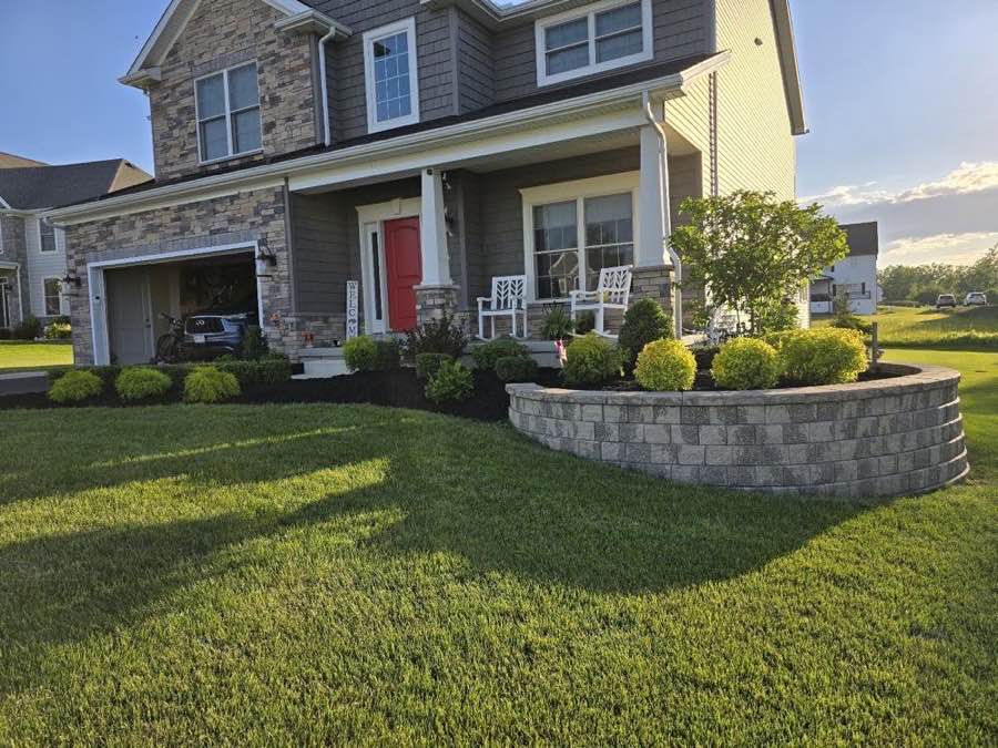 Curved retaining wall planter packed with fresh shrubs